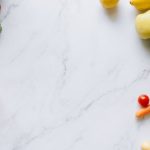 An assortment of fresh fruits and vegetables on a marble background, perfect for healthy lifestyle concepts.