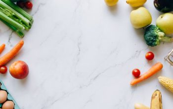 An assortment of fresh fruits and vegetables on a marble background, perfect for healthy lifestyle concepts.